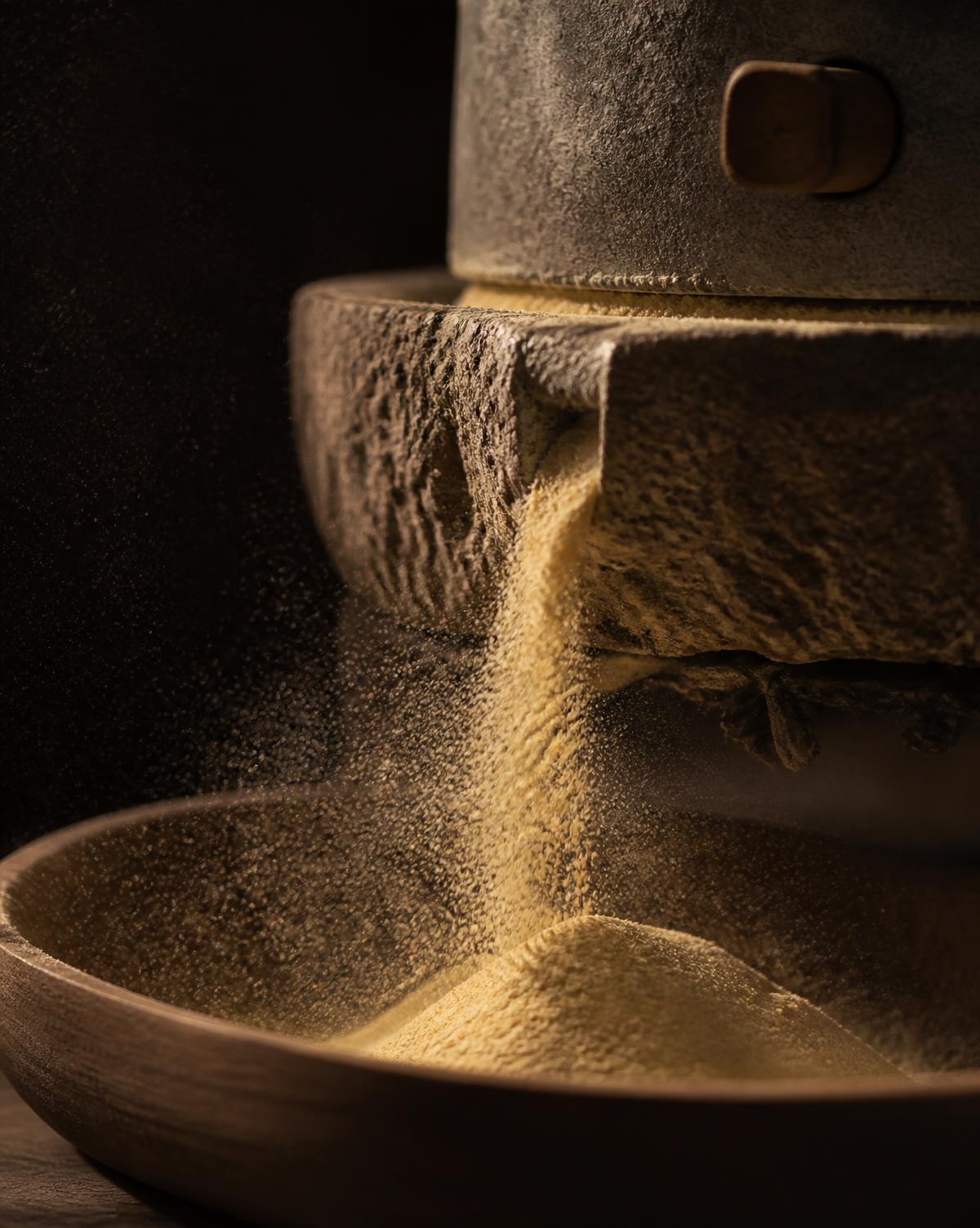 Golden flour falling from a traditional stone mill